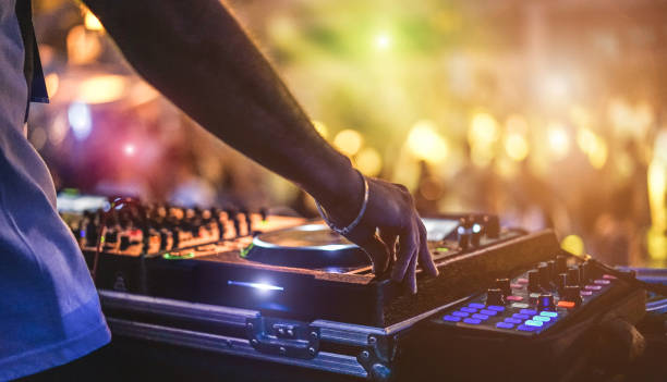 Dj mixing outdoor at beach party festival with crowd of people in background - Summer nightlife view of disco club outside - Soft focus on hand - Fun ,youth,entertainment and fest concept